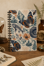 The Natural World Archive dotted notebook standing on a warm natural-history study desk