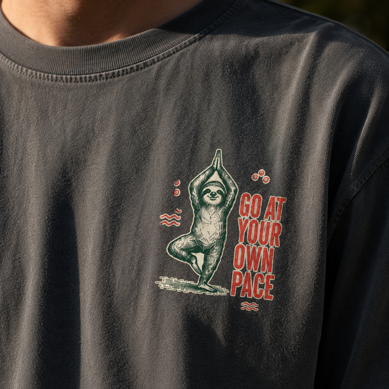 Close-up of the Go at Your Own Pace yoga sloth print, collar stitching, and charcoal Comfort Colors cotton texture