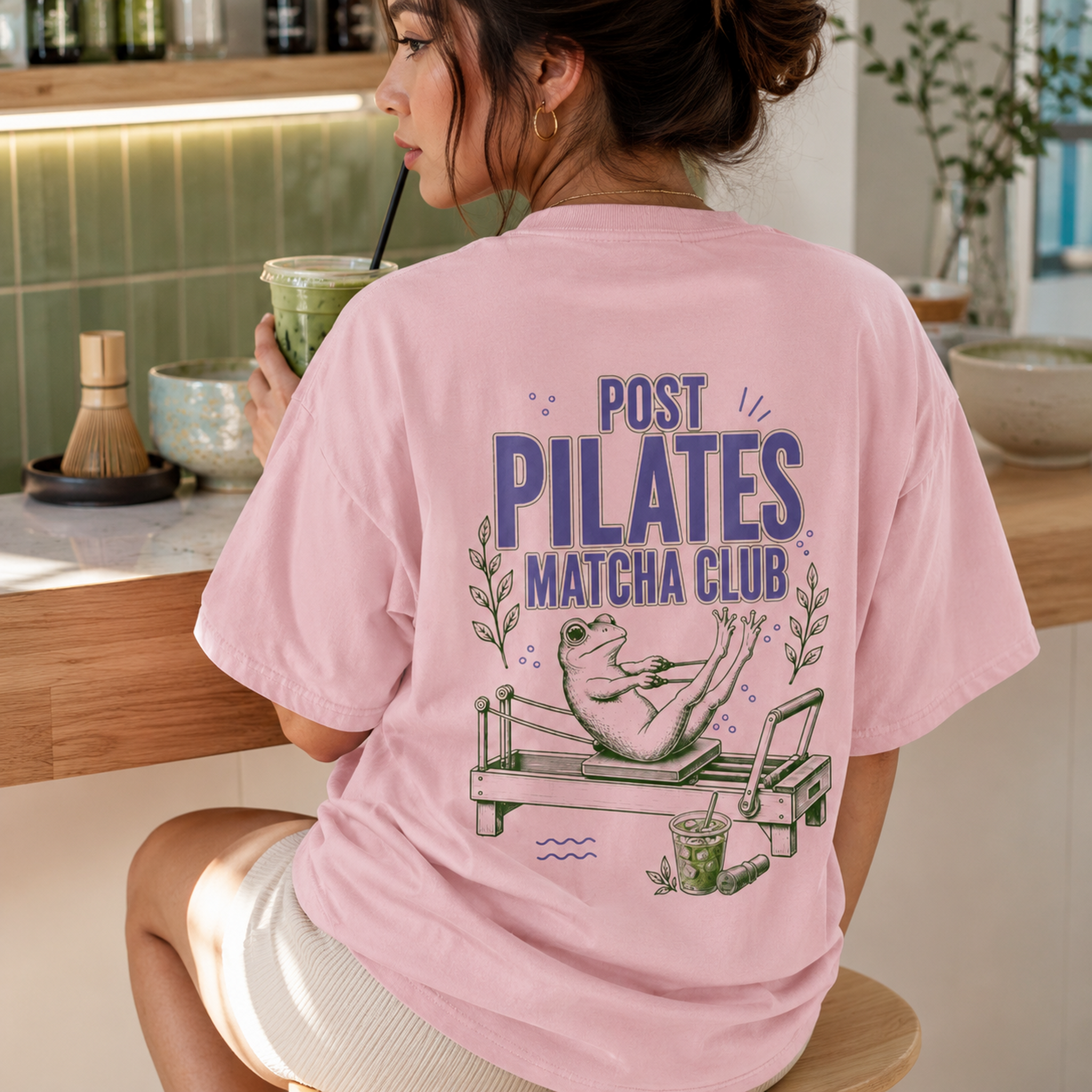 Blossom pink Post Pilates Matcha Club frog tee styled in a matcha shop