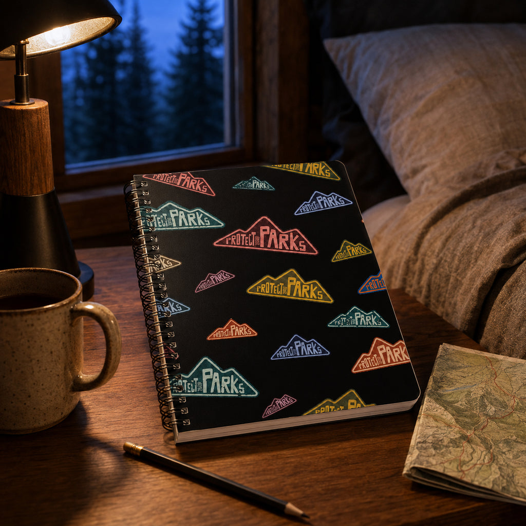 Protect Our Parks black spiral notebook — cabin nightstand