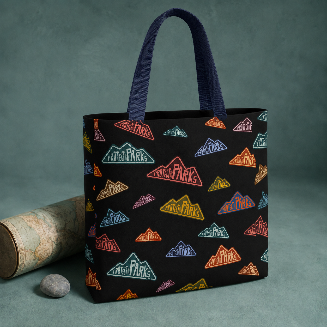 Protect Our Parks tote with navy handles attached inside beside a rolled map